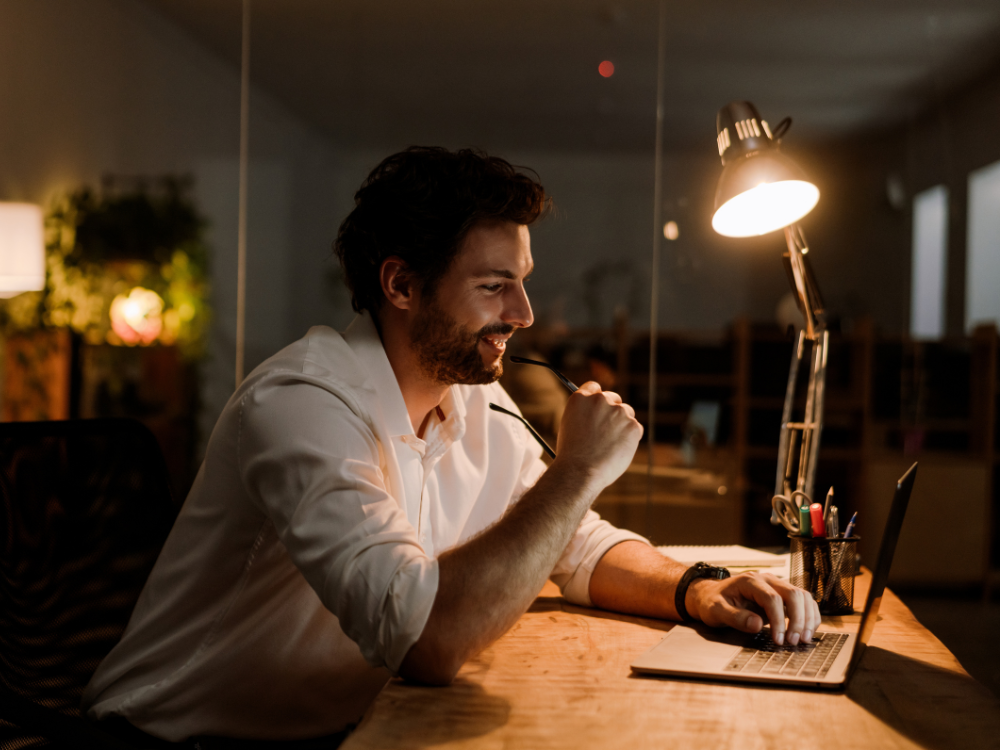 Man on a computer in dim light with a lamp on